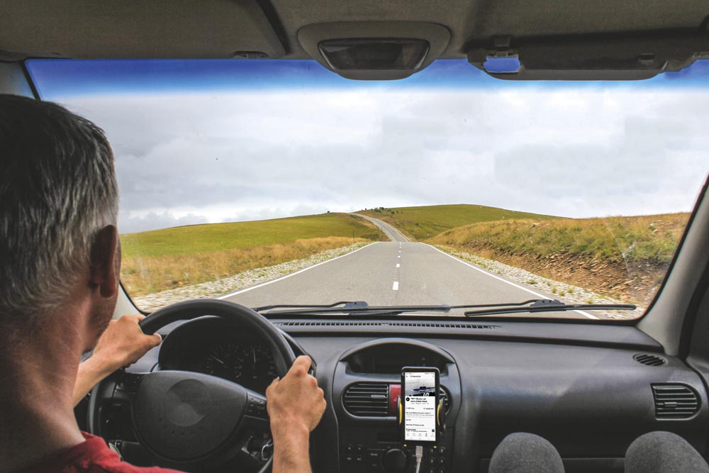 En man sitter i en bil, troligtvis en husbil, och lyssnar på P3 Dokumentär. Man ser bara nacken och armarna på mannen. I passagerarsätet ser man två ben sticka fram.