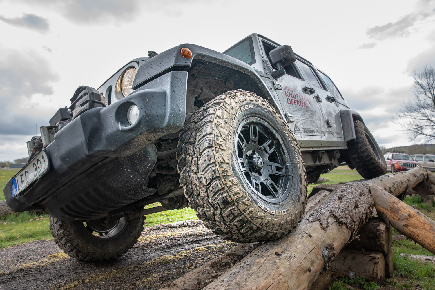 Jeep kör med högerhjulen på några upphöjda stockar och vänsterhjulen är på marken.