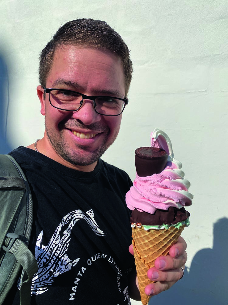 Väldigt glad man äter glassen Kerteminde special. Glassen består av en stor våffla, chokladtäckt glass, ovanpå det mjukglass och en gräddbulle.