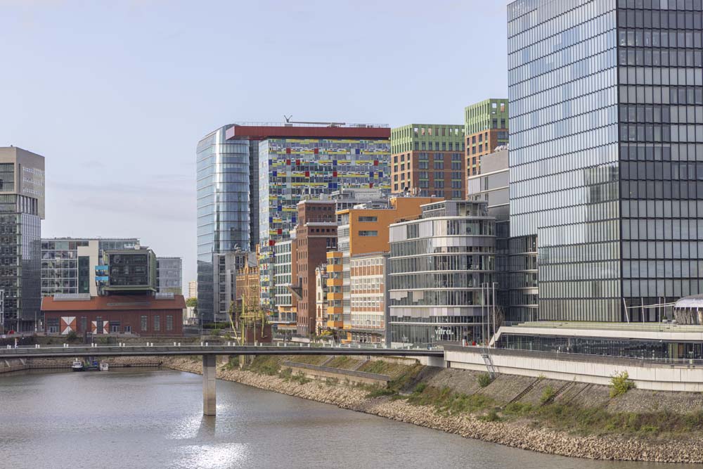 En mix av höga hus med glasfasader och mindre, färgglada hus vid floden.