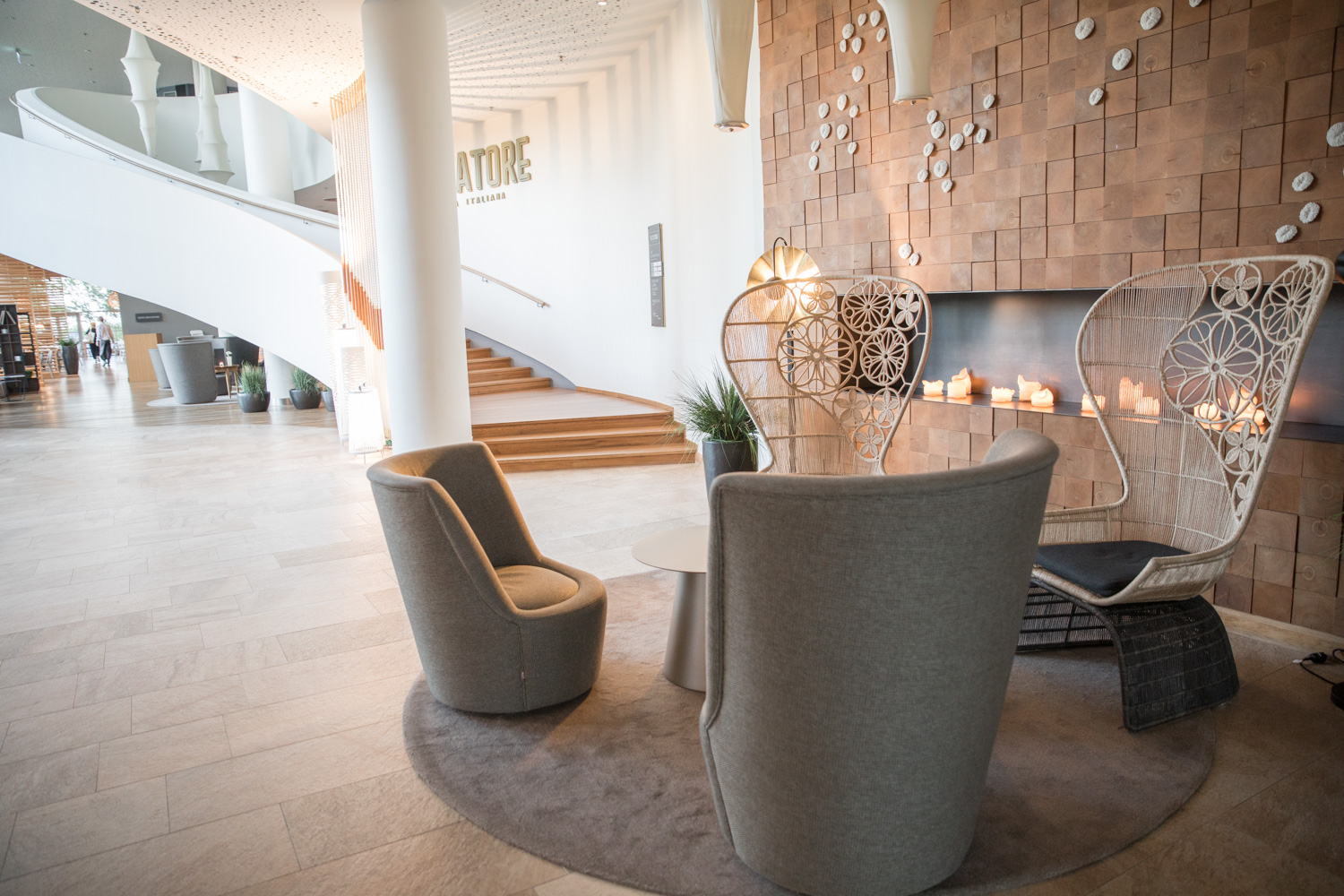 En stor sal med en trappa i bakgrunden. I förgrunden finns en sittgrupp med två höga fåtöljer och två lägre.