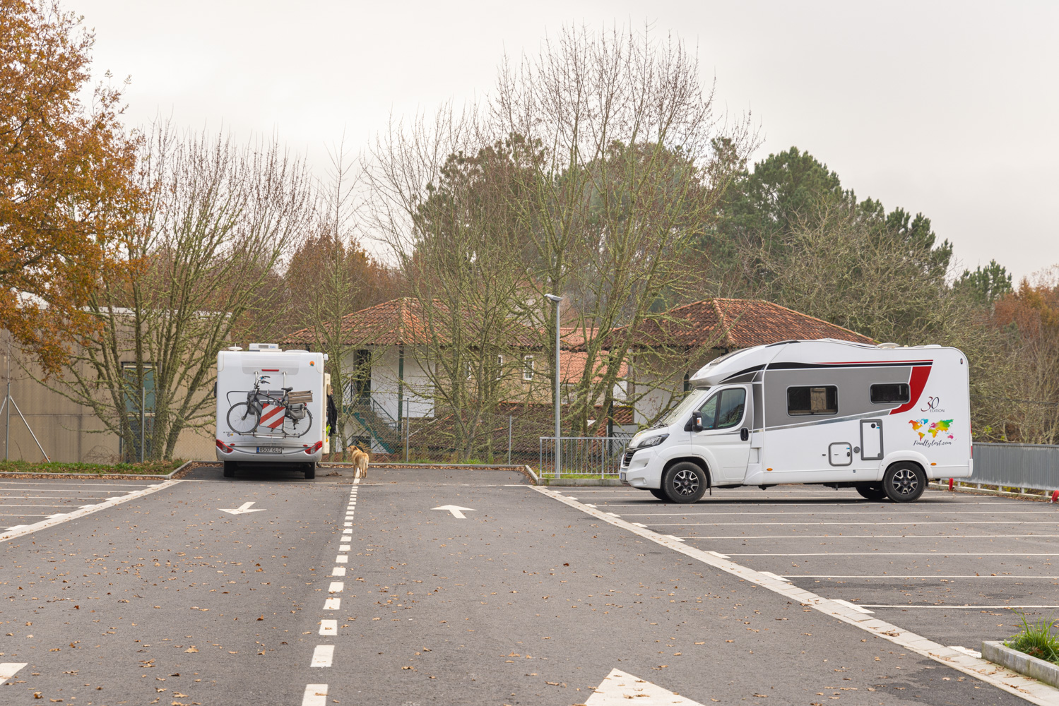En ställplats på asfalt med två husbilar