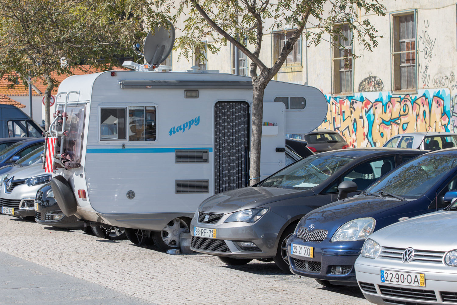 En gatuparkering med bilar och en husbil modell mindre med öppen dörr.