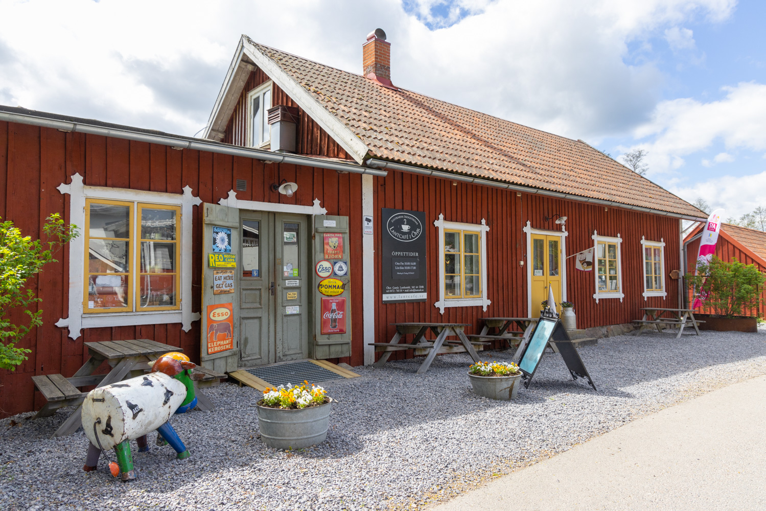 Ett rött hus i gammaldags stil med en lägre tillbyggnad. Den vänstra delen har ett fönster och dubbeldörrar i grågrönt. Den högra delen har tre fönster och en dubbeldörr i gult.