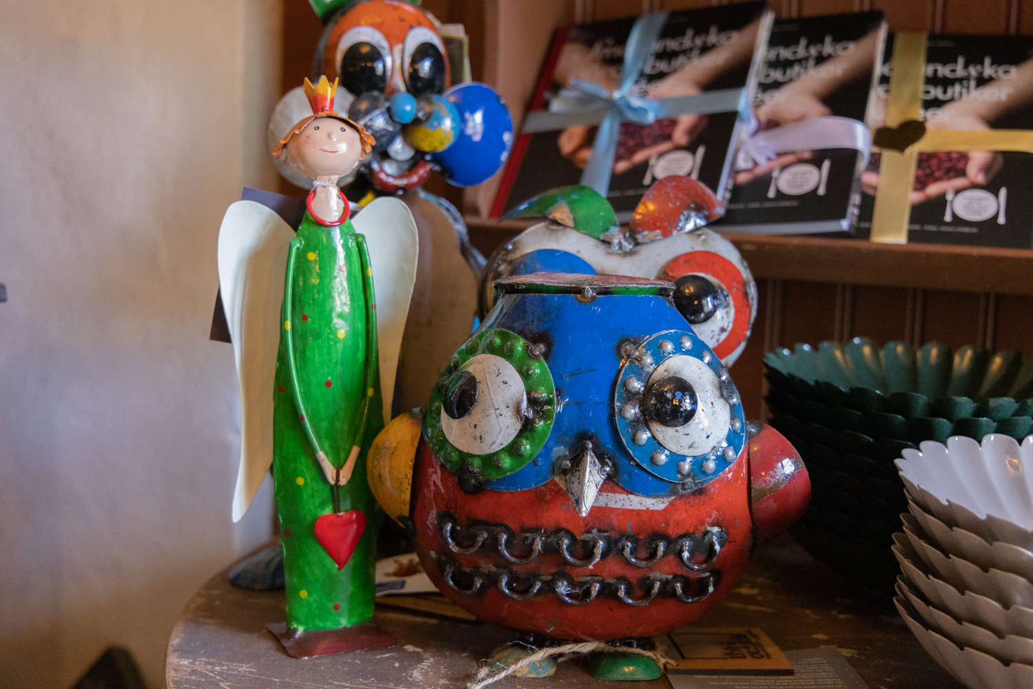 En butikshylla med plåtleksaker, böcker och skålar.